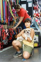 Portrait of smiling preteen boy holding  havanese pup while  in pet shop