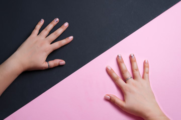Woman's hands with pastel manicure and rings on the fingers on duotone diagonal background.