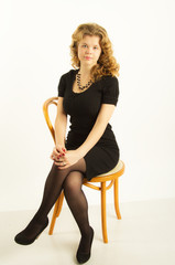 Fototapeta premium image of a girl in a black dress sitting on a chair
