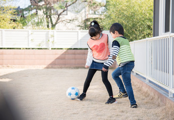 庭でサッカーの練習をする男の子と女の子