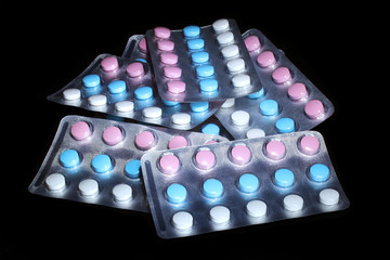  Multicolored pills in several blisters on a black background
