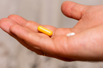 Man taking two pills yellow and white as a medicine