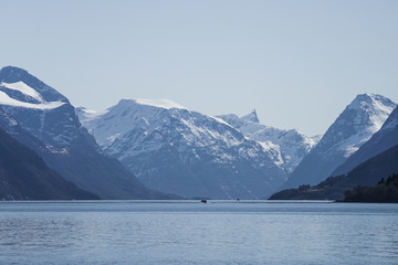 tiny boat driving in huge fjord