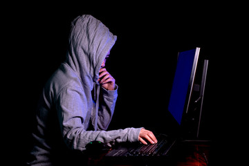 Women hacker breaks into government data servers and Infects Their System with a Virus at his hideout place has dark atmosphere, Lady hooded using laptop on binary code background , Malware conce