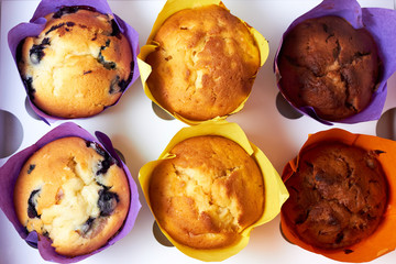 Top view on closeup of white paper box with colorful cupcakes maffins