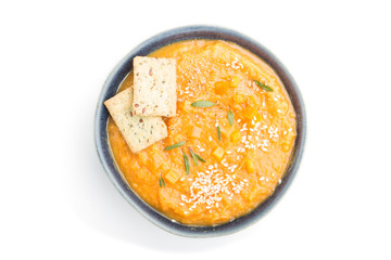 Sweet potato or batata cream soup with sesame seeds and snacks in blue ceramic bowls isolated on white background. top view, close up.