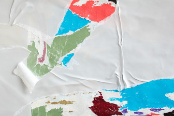 White torn paper placard on billboard with old ripped and peeling posters texture background.