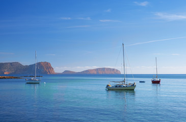 Sailboat docked in front of the beach and the port of Es Canar, Ibiza Island, Balearic islands