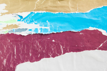 Blue, purple and white torn, crumpled and shabby paper placards on wall billboard. Old colorful...
