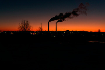from a high pipe above the evening city a large amount of pollutants is thrown into the atmosphere from the production room