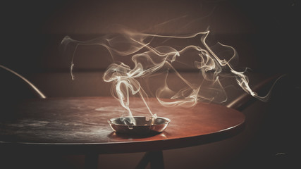  burned cigarette in the ashtray with some smoke