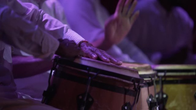 close up slow motion of musician hands playing bongos , performance lifestyle , afro drums men with white traditional costumes , three bongos set