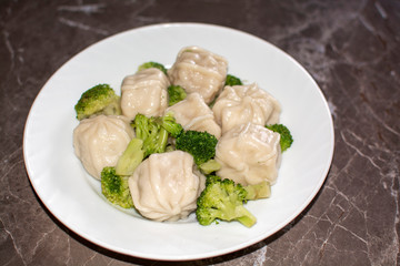 Meat dumplings on a white plate with broccoli