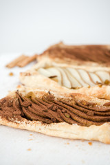 Crunchy puff pastry pie. Homemade baked pie with pears. Top view. Delicious dessert with sliced pear and chocolate powder.