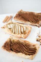 Crunchy puff pastry pie. Homemade baked pie with pears. Top view. Delicious dessert with sliced pear and chocolate powder.
