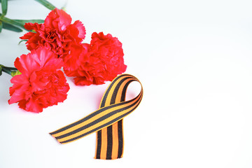 Three red carnation flowers and St. George ribbon - Russian symbol of victory in the second world war, on a white background. Greeting card for May 9 (Victory Day).