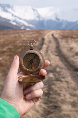 Retro compass in man hand in high mountains. Travel concept. Landscape photography