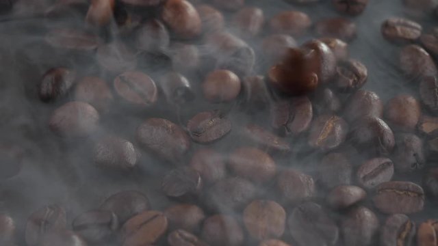 Coffee beans are fried in a pan and mixed with a spoon
