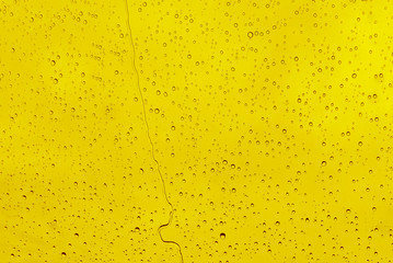 Raindrops on a yellow background. Flowing water from the surface of the window.