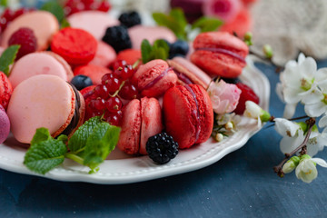 Colorful and bright delicious homemade traditional french dessert - elegant macarons. Natural fruit and berry flavors, sweet creamy stuffing. Top view, close up, macro. Dark blue background