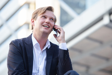 young successful businessman in suit on cell telephone happy, with copy space area.