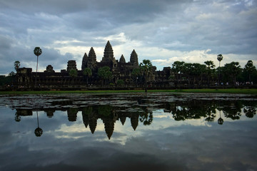 Panoramic view of Angkor Wat and its mirror reflection in the lake at sunrise time. Background of cloudy sky. Cambodia