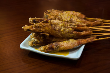 Fried shrimp in batter on skewers on a white rectangular plate.