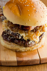 Bacon Cheeseburger with swiss cheese. open faced burger. Traditional classic american restaurant and pub menu item. Cheese burger served with melted swiss cheese lettuce tomato onion and pickle.