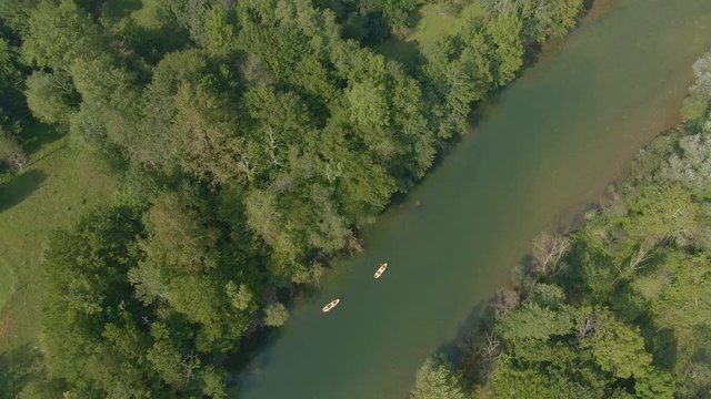 DRONE, TOP DOWN: Carefree tourists paddle their raft along the tranquil river Kolpa on a sunny summer day. Cinematic shot of a group of friends going on a rafting adventure in picturesque Slovenia.