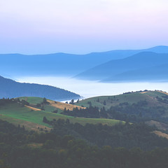 Fototapeta na wymiar Mountain ranges covered with fog against the dawn sky