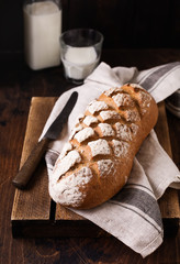 Freshly baked homemade bread with milk on an old wooden table. Rustic style