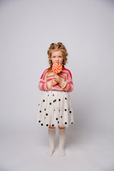 portrait of a girl a blonde child with a Lollipop on a stick smiling in colored clothes on a white background