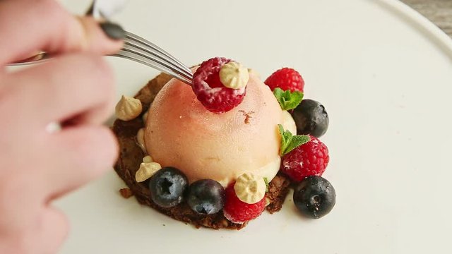 closeup human hands brake icing dessert by fork and knife on white plate