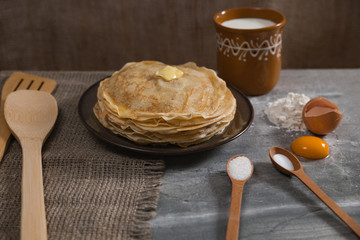Cooking pancakes for holiday breakfast. A stack of pancakes on the table for Maslenitsa. Recipe with ingredients.