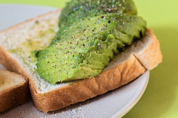 Avocado on toast on the plate over green background