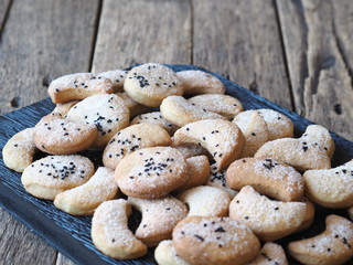 Homemade shortbread cookies sprinkled with sugar with black sesame seeds on a wooden rustic table. Place for text. Photo for the holiday, Shrovetide, Christmas, New Year, Easter.
