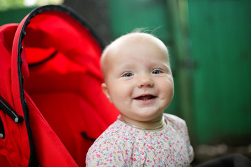 Happy baby in red stroller, warm summer photo