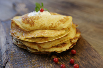 tasty close-up pancakes with sour cream on a wooden rustic background