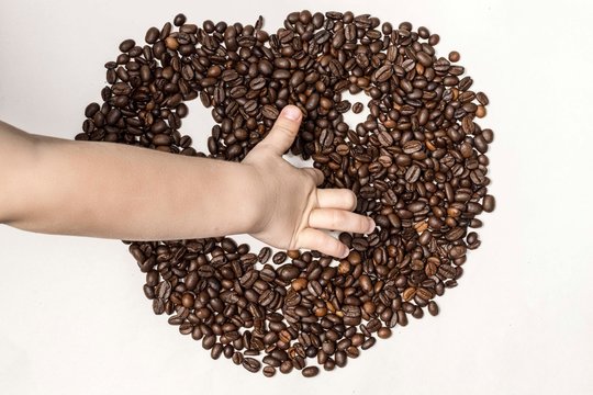 child's hand draws a smiley face with a smile from coffee beans. hollow nai white background