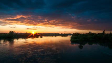Fototapeta na wymiar Sunset over the river in dark orange-blue tones.