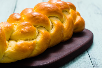 fresh challah bread on cutting board, blue wooden table