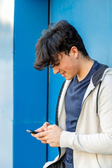 Young boy dressed for sport using his mobile phone on the beach