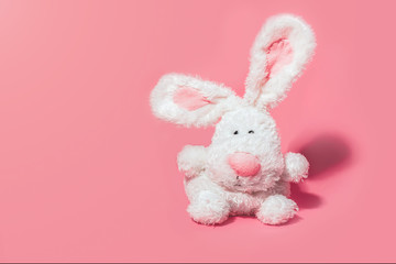 Adorable stuffed bunny on pink background with copy space. Minimal Easter concept.