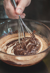 Dessert cream for lava cake cooking with hands in glass bowl