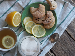 Homemade shortbread cookies sprinkled with sugar with black sesame seeds on a wooden rustic table. Tea party with cookies and lemon. Place for text. Photo for the holiday.
