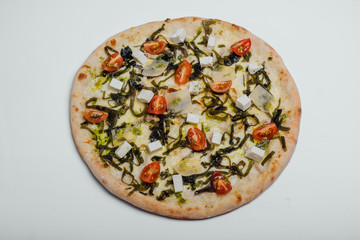 Pizza with tomatoes, feta, parmesan and kale on a white background