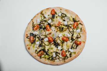 Pizza with tomatoes, feta, parmesan and kale on a white background