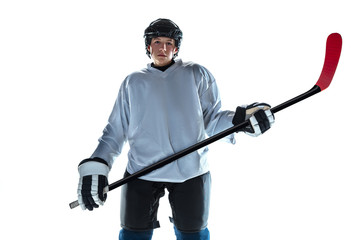 Serious. Young male hockey player with the stick on ice court and white background. Sportsman...