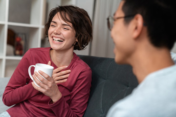Photo of cheerful multinational couple talking and drinking tea