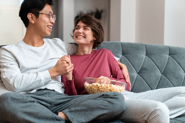 Photo of multinational couple eating popcorn and looking at each other